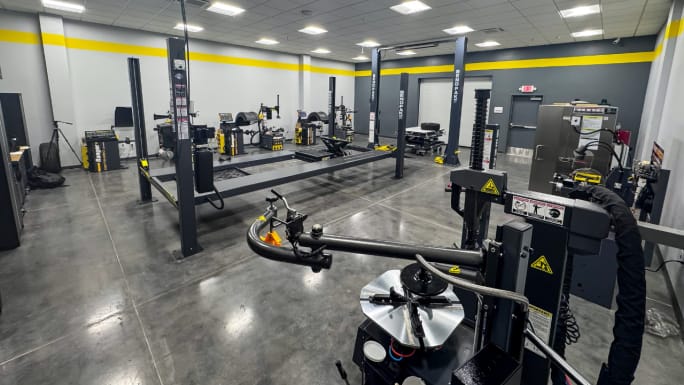 Bright BendPak training showroom featuring vehicle lifts, tire changers, wheel balancers, and alignment equipment in a clean, modern workspace designed for hands-on automotive service training and product demonstrations.