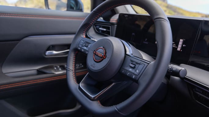 Interior of the 2027 Nissan Kicks Rock Creek showing the steering wheel, digital displays, and orange accent stitching.