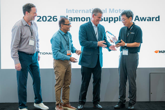 Four men participate in an award presentation at a Hankook event, with one man presenting a crystal trophy beneath a display reading “2026 Diamond Supplier Award.”