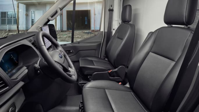 Interior of a Ford Transit Cargo Van showing the driver and passenger seats, steering wheel, digital instrument display, and center touchscreen.