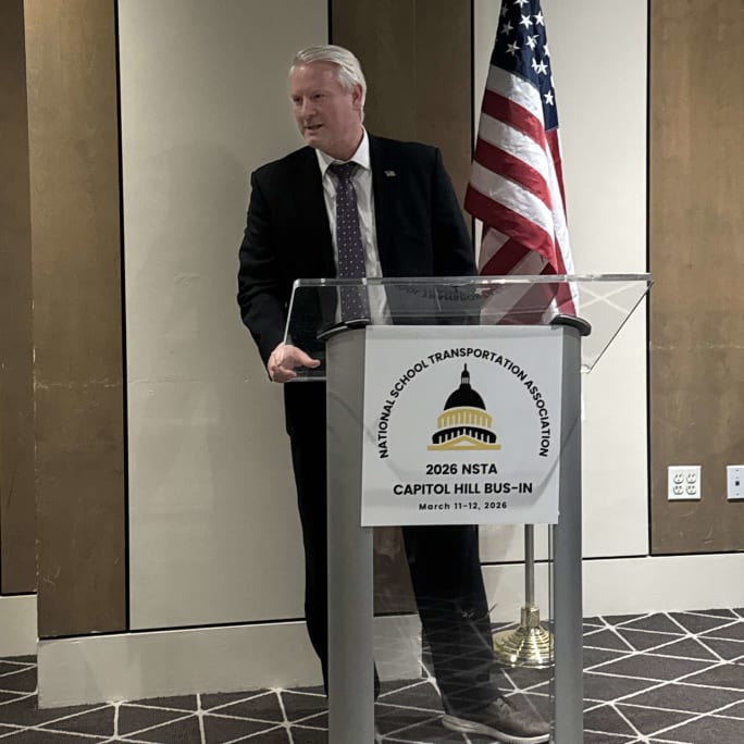 Jesse Elison stands at a podium with NSTA Bus-In signage