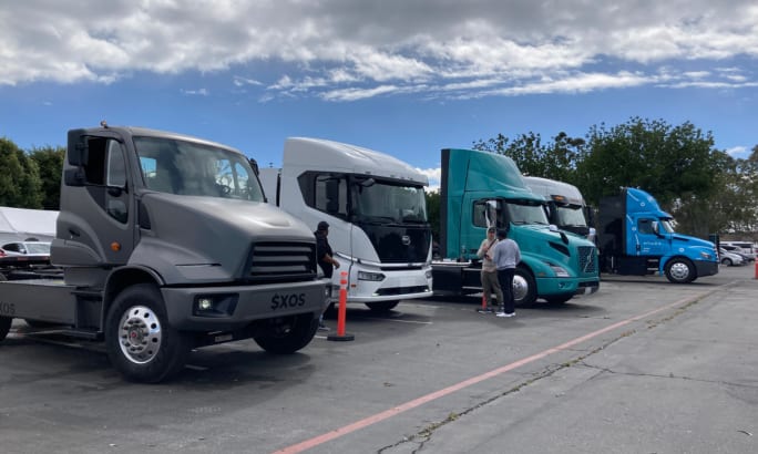 Electric trucks lined up in parking lot.