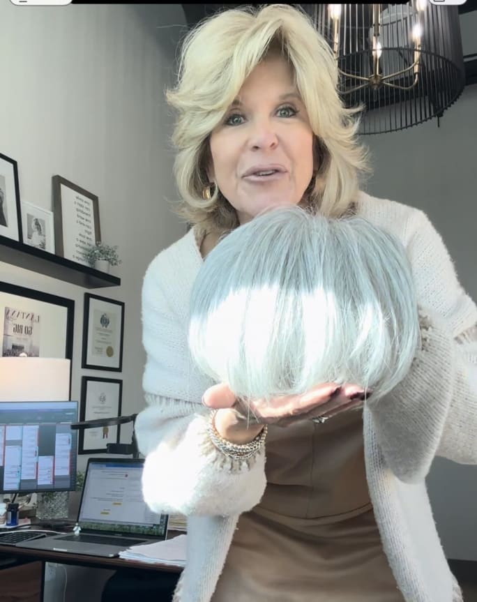 Kim Cloud in her office at Cloud 9 Salon and Spa holding a silver white topper as she films a video.