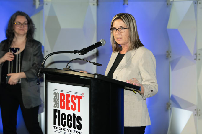 Woman in white suit jacket standing at podium