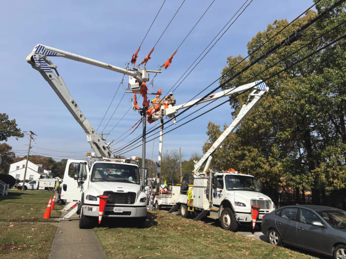 Utility crews working from boom trucks to repair storm-damaged power lines illustrating the role of service vehicles and coordinated recovery during disaster response operations.