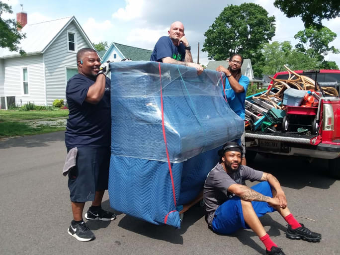 Diverse group of Atlas workers moving piano