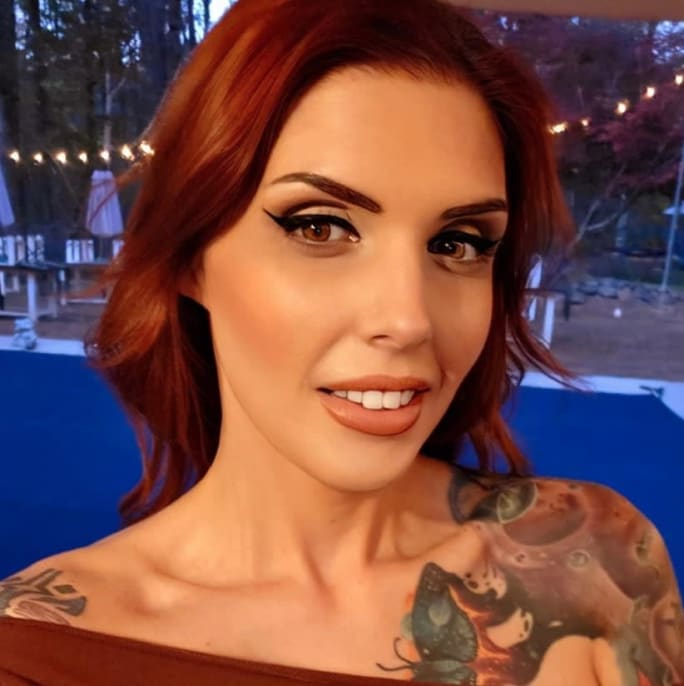 A woman with red hair and tattoos