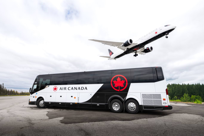 An Air Canada branded motorcoach with an airplane flying over it.