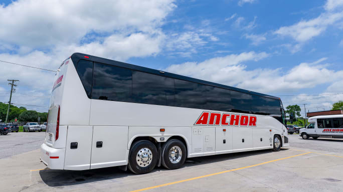 Anchor Transportation motorcoach with mid-sized buses in background.