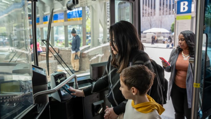 Riders board a Cincinnati Metro bus and tap their phones to pay the fare.