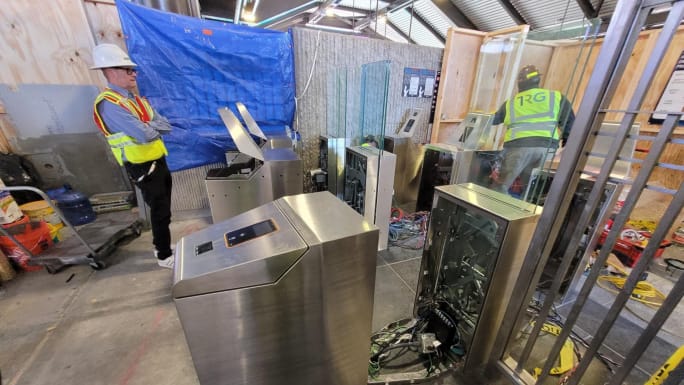 Construction workers installing new faregates and Breeze machines.