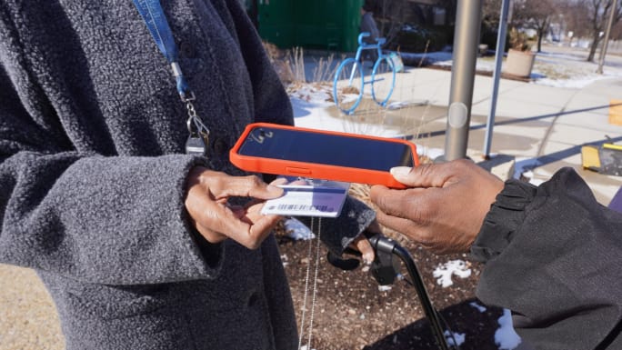 An MCTS employee scanning a rider's fare card with a mobile device.