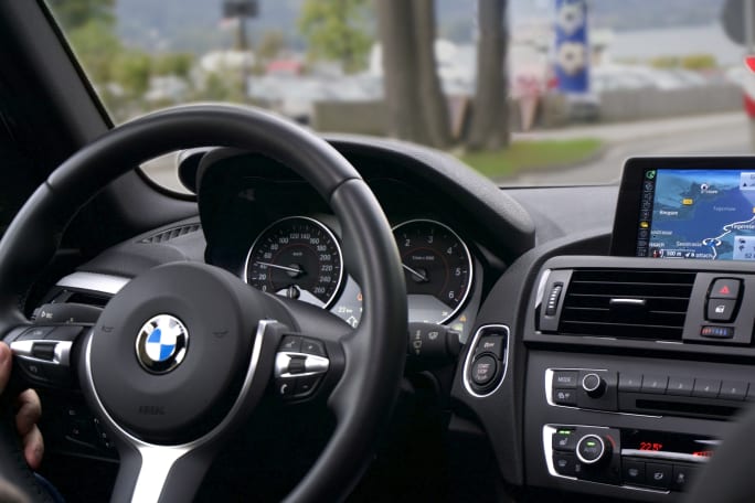 Photo of BMW vehicle dashboard and windshield view of a streetscape ahead