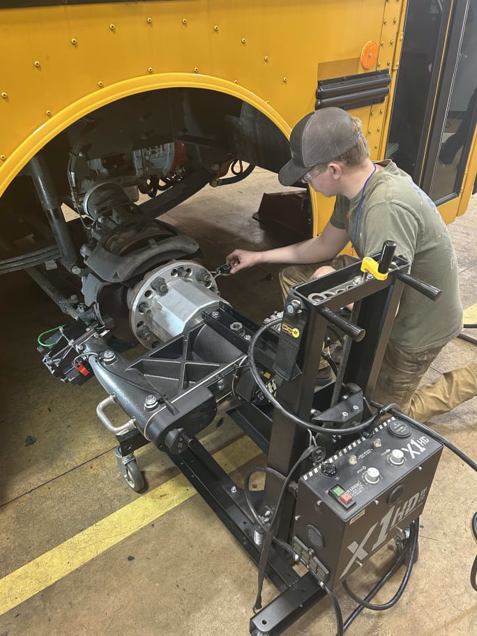 a man uses the Pro-Cut Solutions X1 air disc brake lathe on a school bus