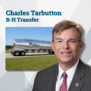 Man in suit with photo of dry bulk tanker in background