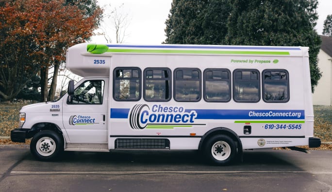 Side view of a white Chesco Connect paratransit bus parked outside.