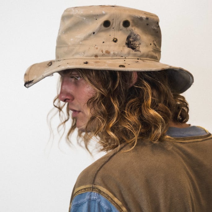 man with curly, shoulder length hair wearing a hat