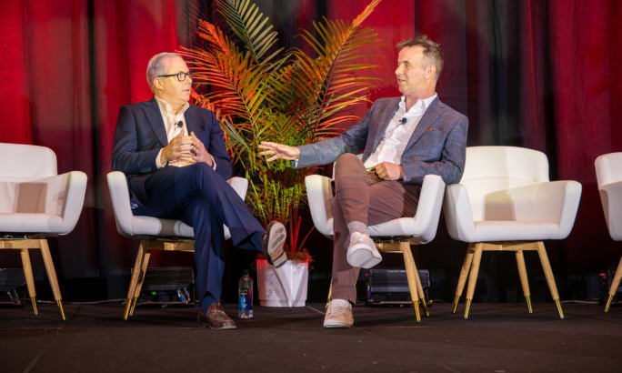 ACRA President Don Lefeve and Chairman Sharky Laguna seated in white chairs on a conference stage accented with a dark red background curtain.