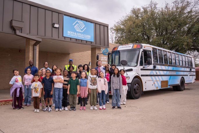 a group of people from the boys and girls club stands next to the donated bus