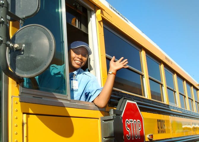 a woman waves from a school bus