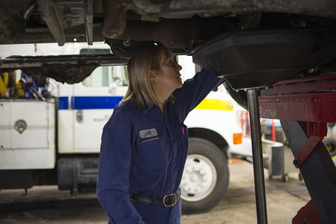 A technician performing an under vehicle inspection