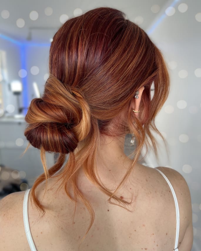 The back of a woman's head, showing red hair and a chignon.