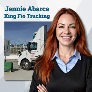 Woman with long red hair standing with arms crossed and a photo of electric truck charging