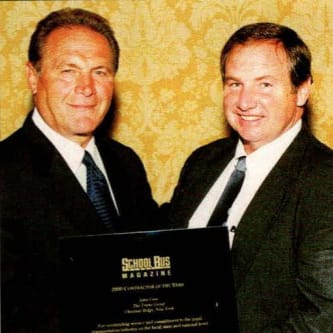 two men in black suits stand together for an award presentation