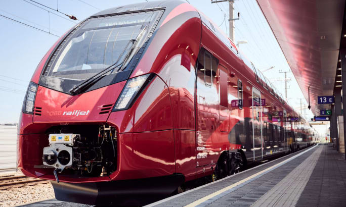 A red Austria Railjet at a station.