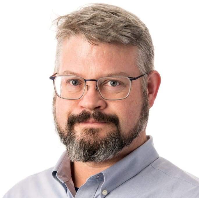 headshot of Ken Hesket, man with glasses and a neat beard and mustache in a collared shirt
