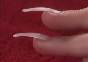 The tip you see on the bottom is untailored, and covers the entire nail.  It also puts pressure on, the puffy skin; notice how it's cutting into  the skin at the tip of the finger. The top tip has been modified in the  contact area so that it covers not more than ore-half of the nail plate.  The extension of the tip has been carved out with a file so that it  sad-dles the puffy skin without exerting any pressure.