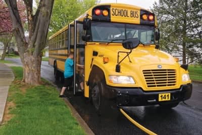  Yellow school bus stopped along a residential street as a student boards through the open front door.