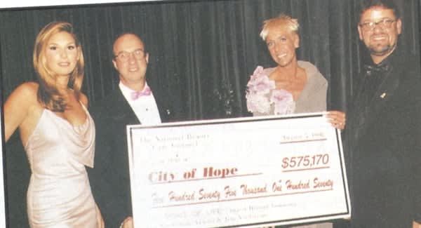 Revlon model Daisy Fuentes, Dr. Charles Balch of the City of Hope, Jan Arnold, and Jim Nordstrom of Creative Nail Design, give a check for $575,170 to the charity.