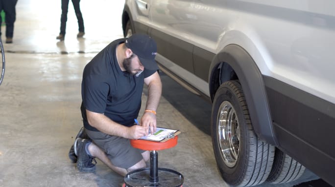 A technician checking a vehicle on a lift. 