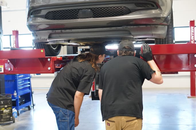 Mechanics looking into car in shop. 