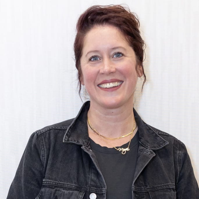 A smiling woman wearing a jean shirt. 