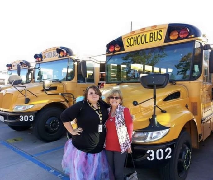 Megan stands with her mother in front of a row of school buses