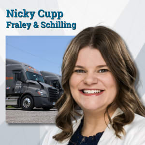 Woman in white suit jacket in front of Fraley & Schilling trucks