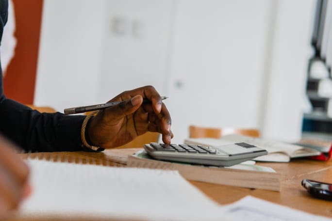 Photo of man's hand poised above calculator on desk
