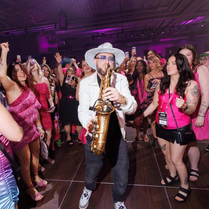 a man playing saxophone in a dancing crowd