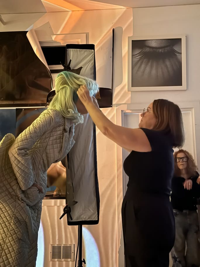A hairdressr adjusts a model's hair on set