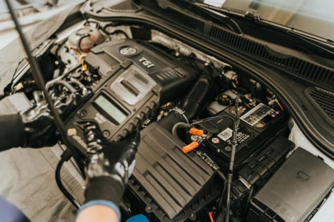 Photo of mechanic's hand's holding a device over a vehicle's engine