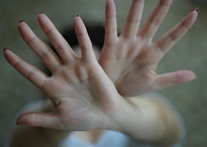 Photo of a woman with her hands crossed in front of her face