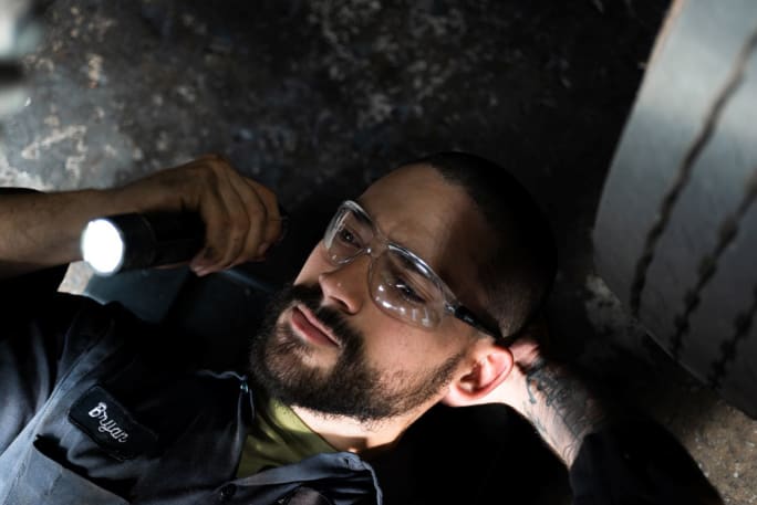 Technician under truck with flashlight