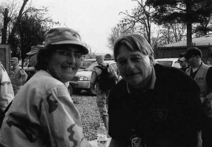 A black and white portrait of Tracy Voigt in military fatigues with Blake Clark.