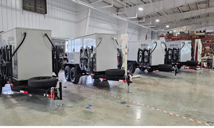 A row of box white trailer charging and battery storage hubs.