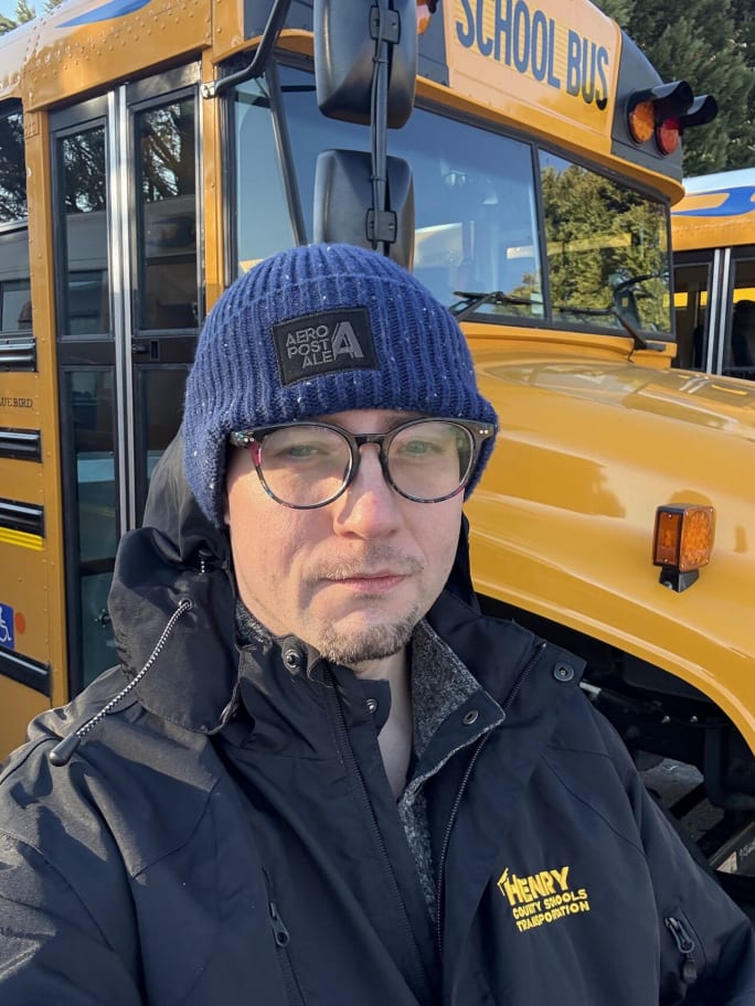 a man stands in front of a school bus