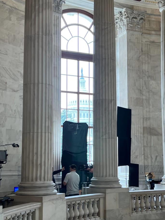 U.S. Capitol seen through a window bracketed by rotunda columns.