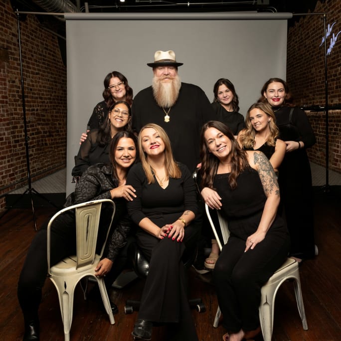 The team from All Things New pose in all black attire on a photo set.