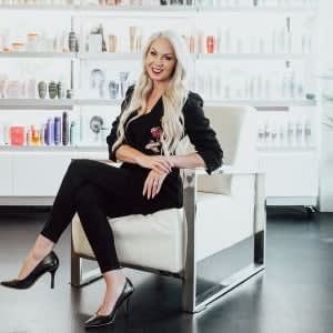 Salon owner AnneMarie Krainich seated in a modern beauty space, reflecting strong leadership, client-focused culture, and long-term business growth through loyalty.